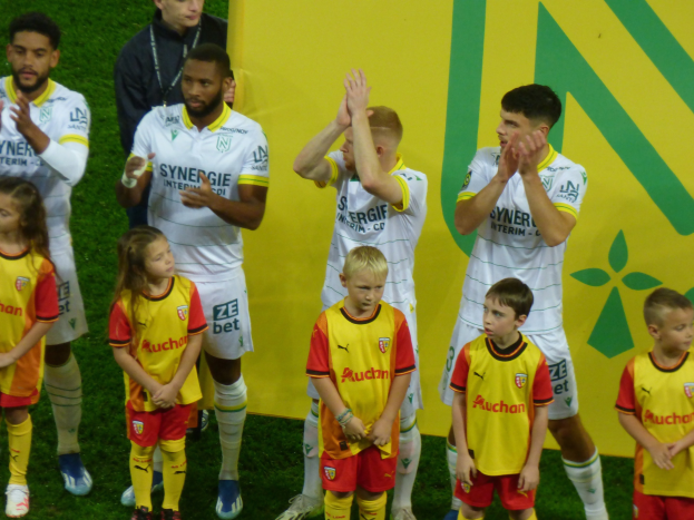 Eine Gruppe junger Fußballspieler in Uniformen klatscht auf einem Ligue-1-Feld in celebration
