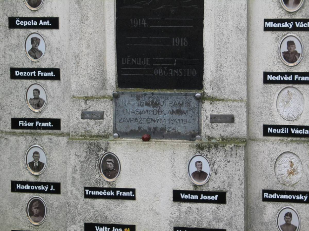 Eine Gedenktafel an einer Wand, die Fotos von Individuen und Text enthält, gewidmet denen, die im Zweiten Weltkrieg ihr Leben verloren haben.