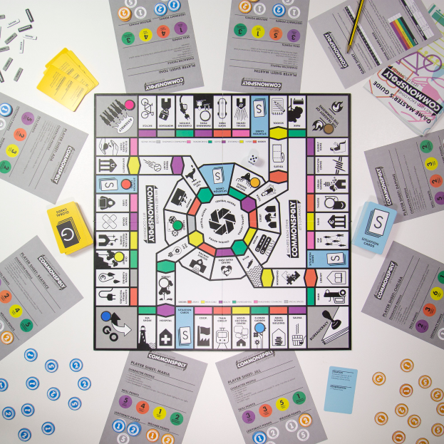 Ein Monopoly-Brettspiel ist auf einem Tisch umgeben von verschiedenen Karten, Papieren und einem Bleistift aufgebaut.