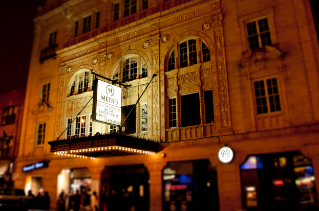 Ein gelbes Geb├Ąude mit Gesch├Ąften im Erdgeschoss, eines davon hat ein wei├čes Schild mit der Aufschrift "Metro"