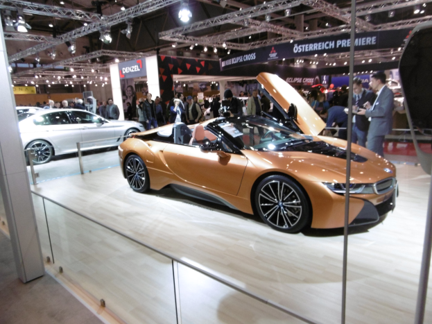 Ein glänzend schwarzes BMW i8 Cabrio mit Chromakzenten auf der Internationalen Automobil-Ausstellung in Frankfurt umgeben von formell gekleideten Besuchern.