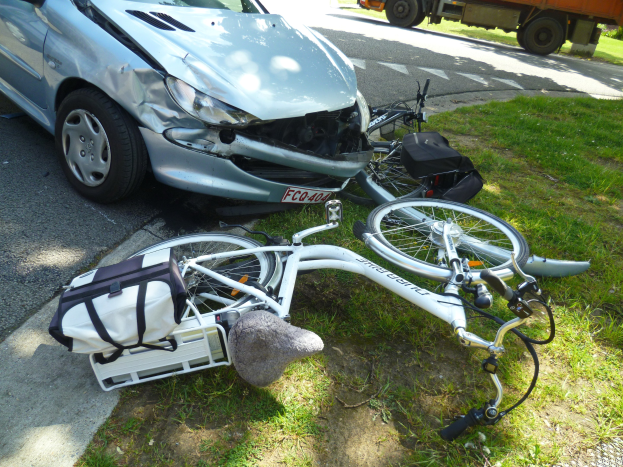 Auto am Straßenrand mit einem Fahrrad auf dem Gras in der Nähe, Trees und klarer blauer Himmel im Hintergrund.