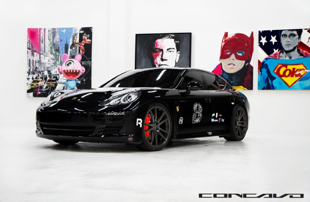 Ein schwarzer Nissan-Sportwagen ist mit Cartoon-Postern im Hintergrund und einer kleinen Inschrift unten zu sehen.