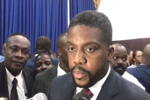 Ein Mann im Anzug und Krawatte spricht vor einem Publikum in ein Mikrofon, mit Vorhängen und einer Wand im Hintergrund, wahrscheinlich in Reaktion auf die Nachricht seiner lebenslangen Haftstrafe.