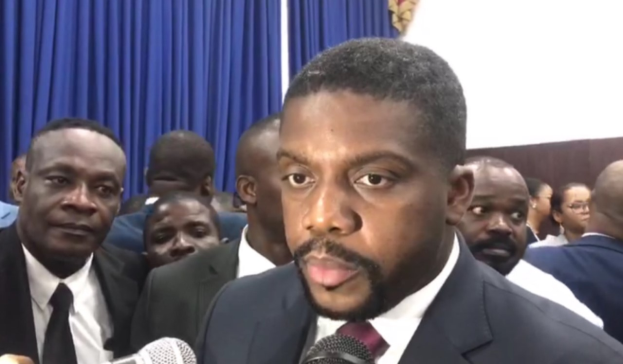 Ein Mann im Anzug und Krawatte spricht vor einem Publikum in ein Mikrofon, mit Vorhängen und einer Wand im Hintergrund, wahrscheinlich in Reaktion auf die Nachricht seiner lebenslangen Haftstrafe.