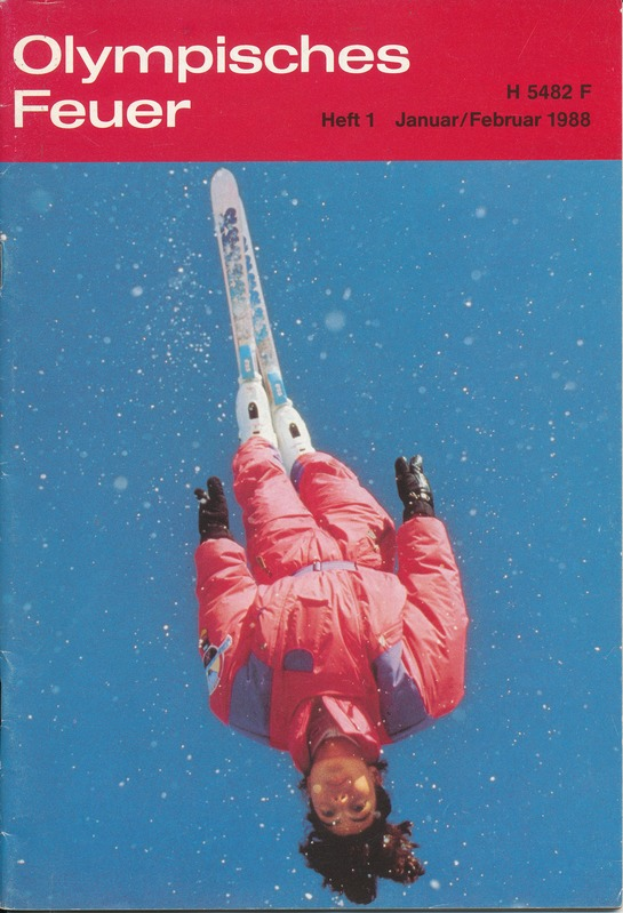 Ein Buchumschlag mit einem Skifahrer in der Luft mit einem entschlossenen Gesichtsausdruck, der eine Skiuniform trägt, mit der Aufschrift "Olympische Spiele Feuer - Heft 1 - Januar/Februar 1988".