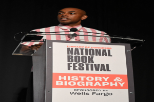 Ein Mann steht an einem Rednerpult mit einem Mikrofon und spricht bei einem Abendevent mit dem Titel "National Book Festival Geschichte & Biografie".