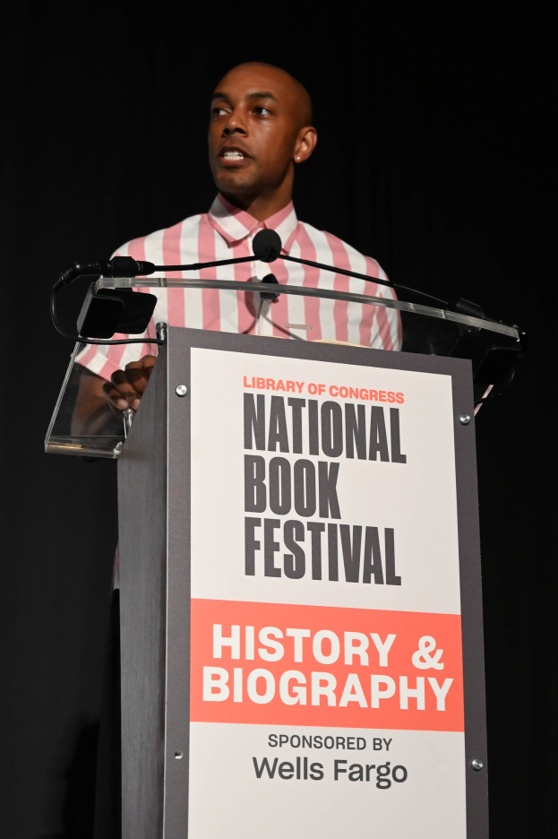 Ein Mann steht an einem Rednerpult mit einem Mikrofon und spricht bei einem Abendevent mit dem Titel "National Book Festival Geschichte & Biografie".