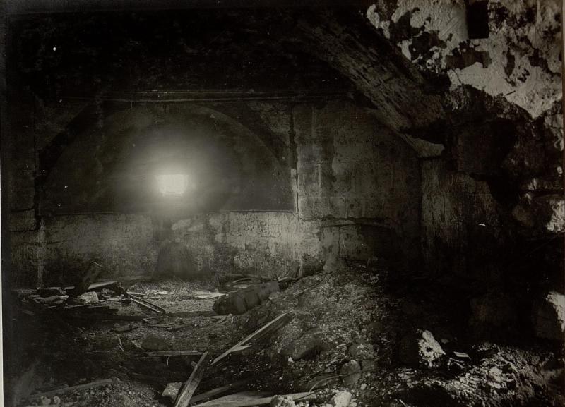 Schwarzes und weißes Foto eines zerfallenden Tunnels in den Berliner Mauerruinen, mit Schutt auf dem Boden und einem Licht am Ende.
