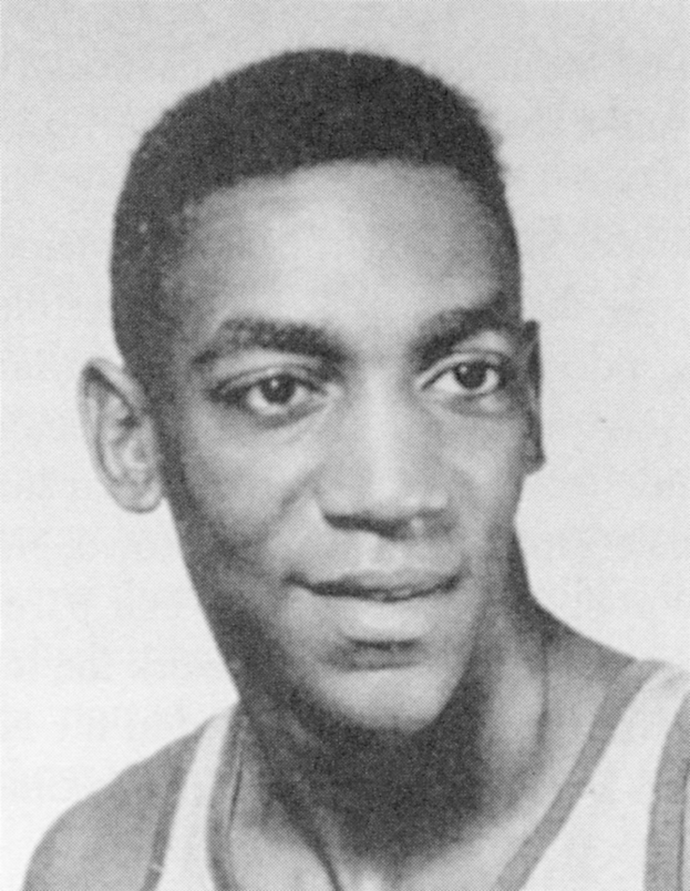 Ein Mann in einem weißen "Basketball Hall of Fame"-Trikot, der warm lächelt mit zurückgekämmtem Haar.