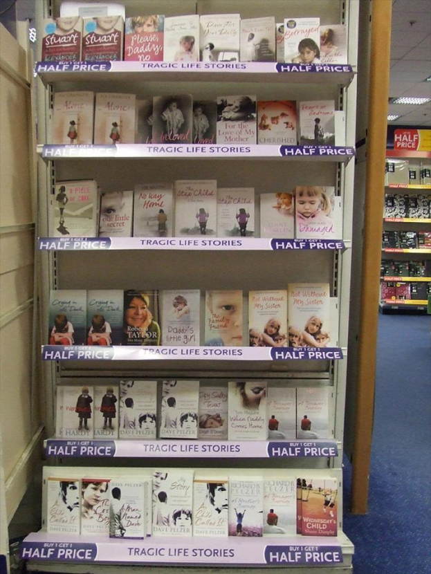 Ein Innenblick, der ein Bücherregal mit vielen Büchern, eine Tür auf der linken Seite, ein weiteres Regal im Hintergrund mit ein paar Gegenständen und Lampen an der Decke zeigt.