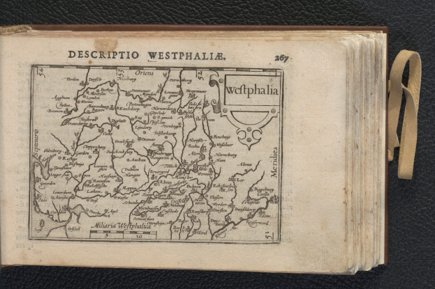 Ein aufgeschlagenes Buch mit einer detaillierten Karte von Westphalien, das auf einer schwarzen Oberfläche liegt.