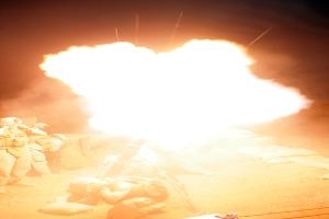 Mehrere Personen in Uniform und Helmen befinden sich auf einem Gelände mit ein paar verstreuten Taschen, wobei in der Mitte des Bildes ein Feuer brennt.