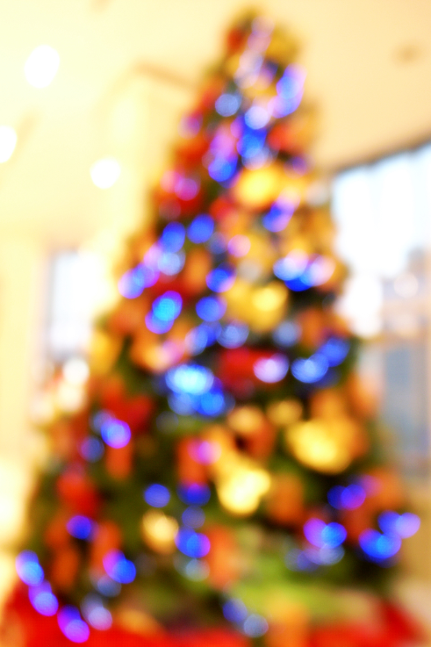 Eine unscharfe Innenaufnahme mit einem Weihnachtsbaum in der Mitte, der mit Lichtern und Schmuck verziert ist.