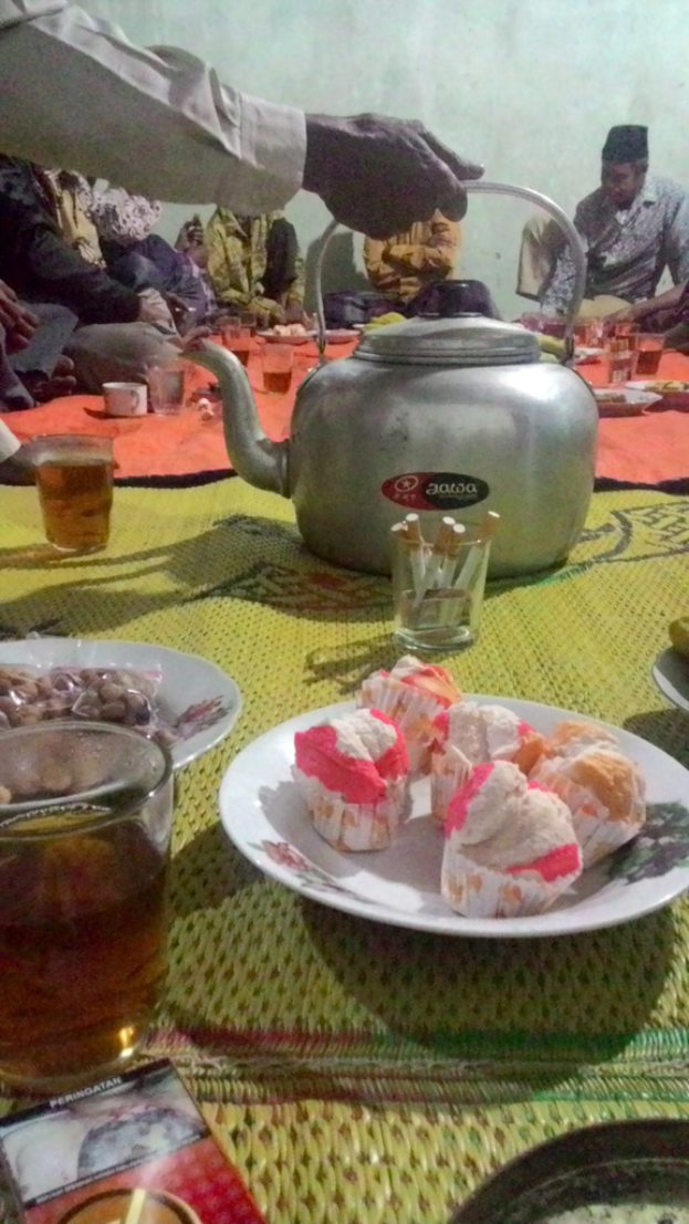 Ein Raum mit wenigen Menschen und einem Tisch mit Tellern, Gläsern und Speisen.