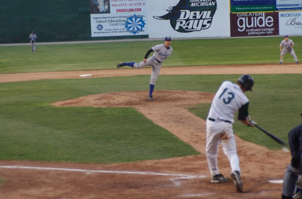 Eine Gruppe von Menschen beim Baseballspielen auf einem Feld mit Bannern im Hintergrund.