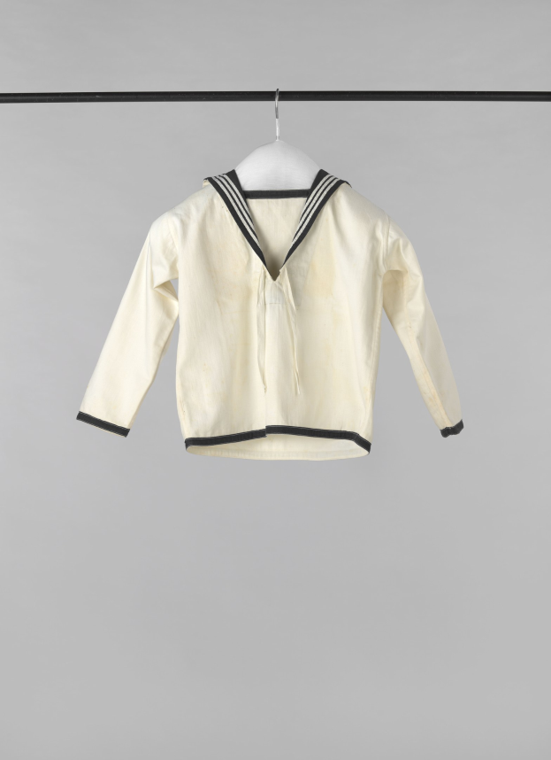 Weißer Matrosenjacke mit Kragen, langen Ärmeln und Knopfleiste, die an einer Wäscheleine gegen einen weißen Hintergrund hängt, aus leichtem Rippenstoff hergestellt.