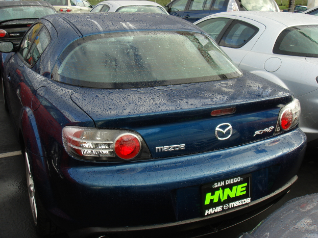 Mehrere Autos stehen auf einem Parkplatz mit einem Schild, das Text enthält.