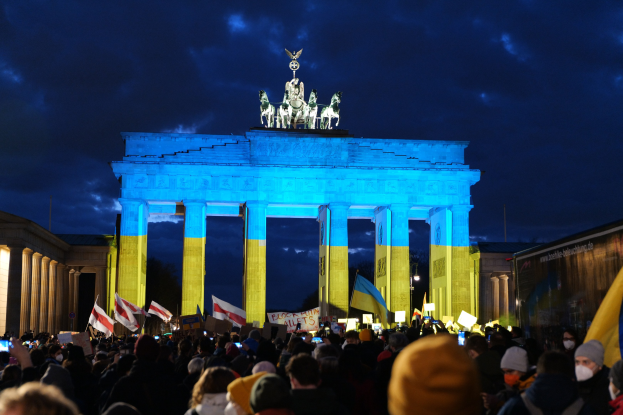 Menge mit Fahnen und Plakaten vor dem Brandenburger Tor mit einer Banner auf der rechten Seite.