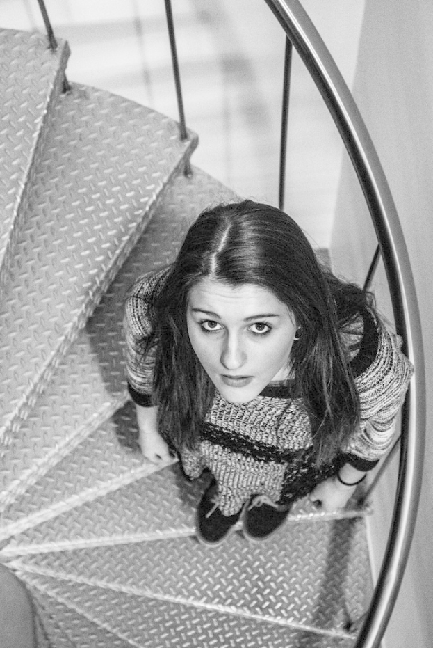 Ein Mädchen steht in der Mitte des Bildes auf einer Treppe.