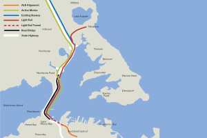 Karte einer Stadt mit einer roten Linie, die die geplante Bahnroute markiert, einschließlich Haltestellen und Details der Umgebung.