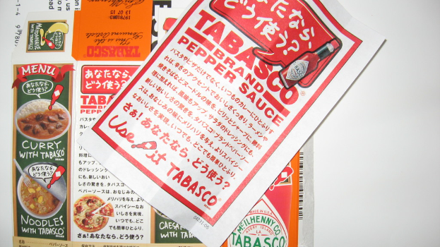 Ein Prospekt, das Pfeffersoße bewirbt, mit einem darunter liegenden Blatt, das Werbung für verschiedene Currys enthält.