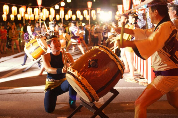 Männer, die auf einem Fest mit Lichtern an der Decke Trommeln spielen.