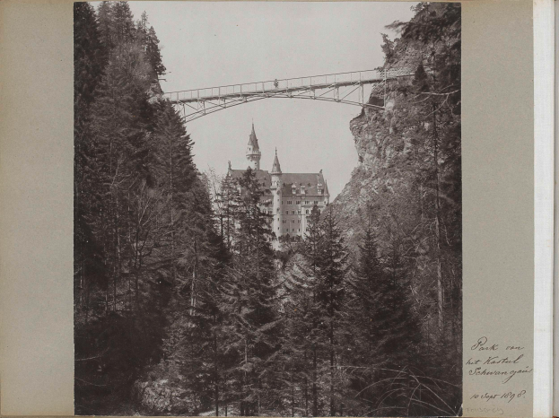 Ein Schwarz-Weiß-Foto der Neuschwansteinburg in Deutschland mit einer Brücke im Vordergrund, umgeben von Bäumen und Text auf der rechten Seite.