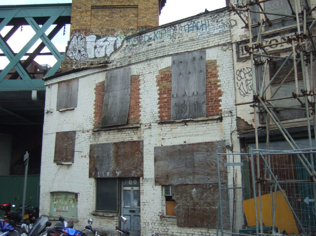 Ein Hausgebäudestruktur in der Mitte, Fahrzeuge unten, ein Pfahl links, eine Brücke oben und eine hölzerne Bambusstruktur rechts.