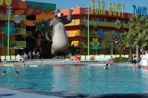 Ein Schwimmbad mit blauem Wasser und Menschen, die darin schwimmen, mit Cartoon-Bildern und Stangen im Hintergrund.