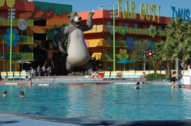 Ein Schwimmbad mit blauem Wasser und Menschen, die darin schwimmen, mit Cartoon-Bildern und Stangen im Hintergrund.