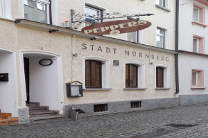 Gebäude mit einer "Stadt Nurnberg"-Aufschrift, Fenstern, einer Tür, einer Treppe und einem Müllimer im Vordergrund.