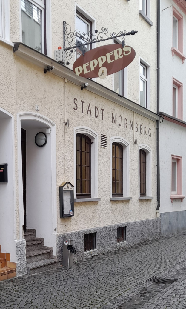 Gebäude mit einer "Stadt Nurnberg"-Aufschrift, Fenstern, einer Tür, einer Treppe und einem Müllimer im Vordergrund.