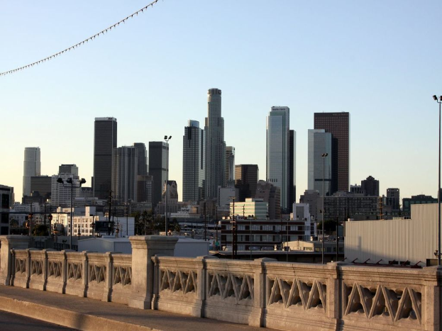 Ein Geländer im Vordergrund mit hohen Gebäuden und Masten im Hintergrund.