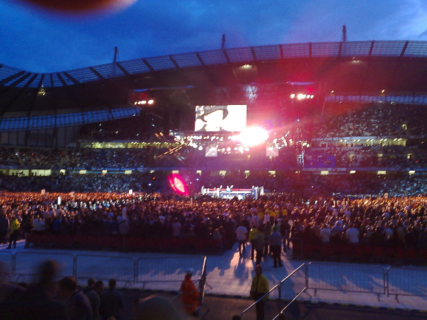 Eine Konzerthalle mit Menschen, Scheinwerfern und einem Projektionsschirm.