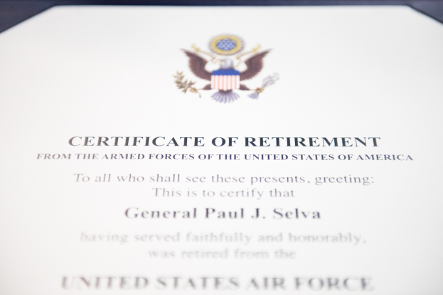 Rahmenurkunde für den Ruhestand der United States Air Force mit blauem Rand, das eine zentrale Sternschild-Logos umgeben von einem Lorbeerkranz und einer 'Ruhestand'-Bannert trägt, alles in schwarzer Tinte auf weißem Papier.