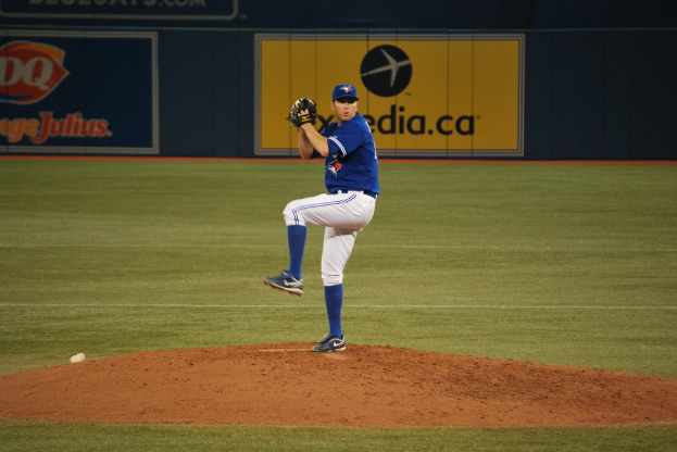 Ein Spieler steht auf dem Boden und hält einen Ball in der Hand, im Hintergrund ist eine große Fahne mit Text und Bildern zu sehen.
