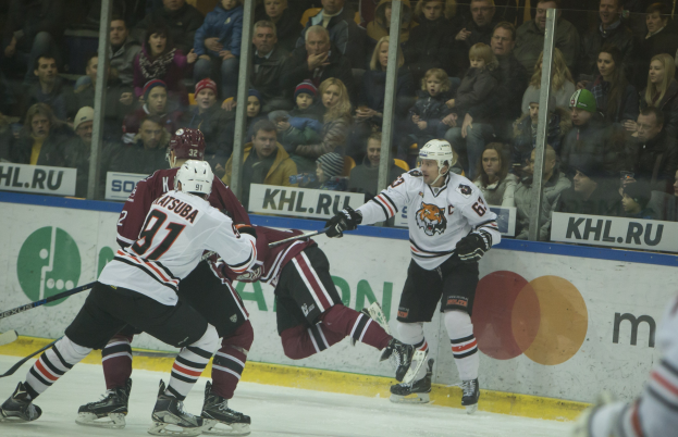 Eine Gruppe von Menschen, die auf einem Eis Eis hockey spielt, mit Helmen und Sportbekleidung, vor einem Publikum und Werbetafeln