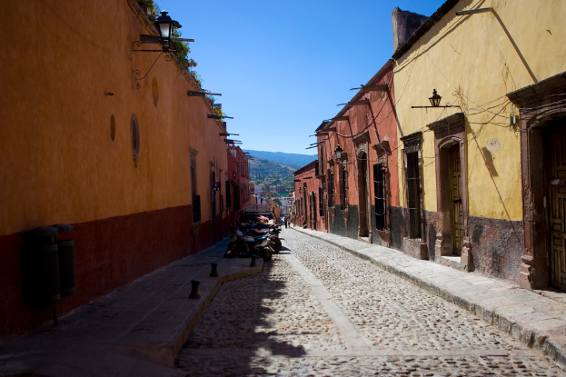 Eine leere Straße mit zahlreichen parkenden Fahrrädern neben mehreren Gebäuden, wobei eines Gebäude prominent in den Vordergrund ragt.