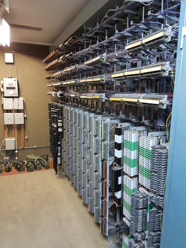 Großer Raum voller Server, Kabel und elektronischer Geräte, typisch für eine Rechenzentrumseinrichtung.