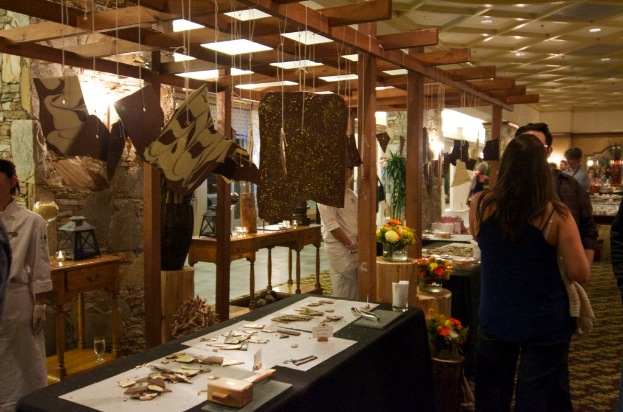 Eine Gruppe von Menschen, die um einen Tisch in einem Restaurant stehen, mit Blumentöpfen, Kerzen und hängenden Leuchten.