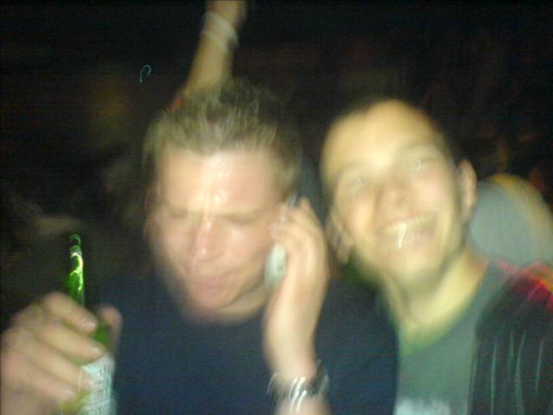 Ein Mann mit Bierflasche und Mikrofon, daneben ein Mann, der lächelt.