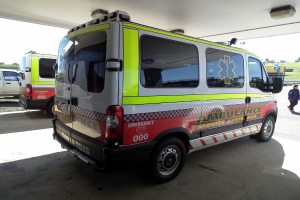 Zwei Krankenwagen nebeneinander unter einem Dach geparkt, mit einer Person auf der rechten Seite und einem Mann neben dem linken Krankenwagen.