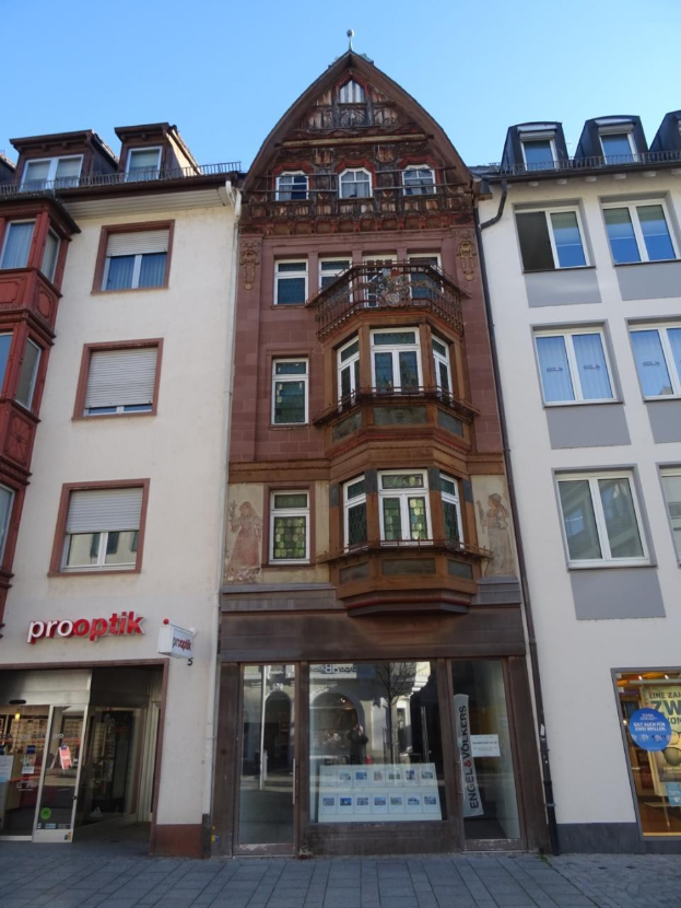 Gewerbliches Gebäude mit vielen Fenstern zum Verkauf an einer Straße in Heidelberg, Deutschland, unter einem klaren blauen Himmel.
