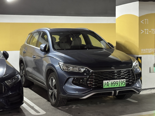 Zwei Autos nebeneinander in einer Garage mit einer Wand und einer Deckenlampe geparkt, begleitet von einem Schild in Chinesisch auf der rechten Seite.