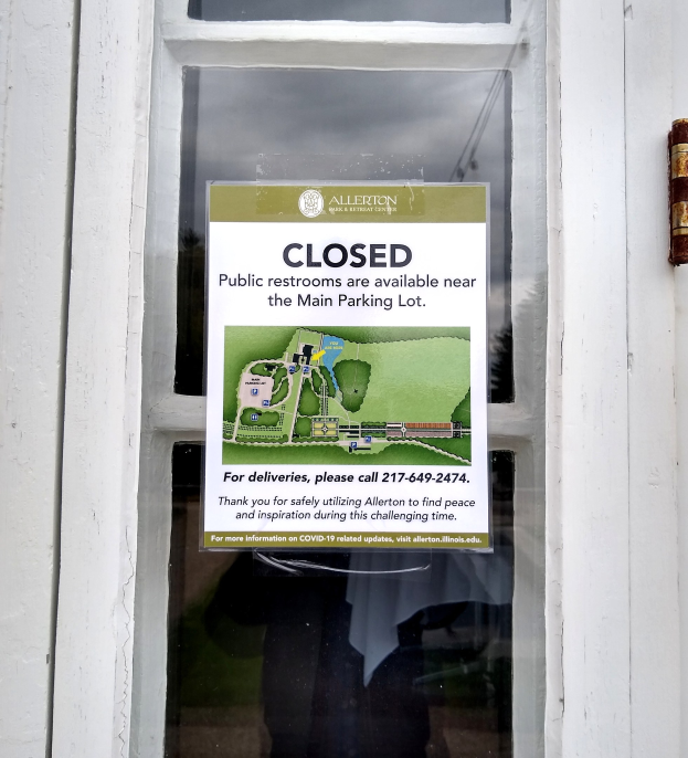 Gläserne Tür mit einem Schild, auf dem "Geschlossene öffentliche Toiletten in der Nähe des Hauptparkplatzes" steht, und einem unklaren Objekt auf der rechten Seite.