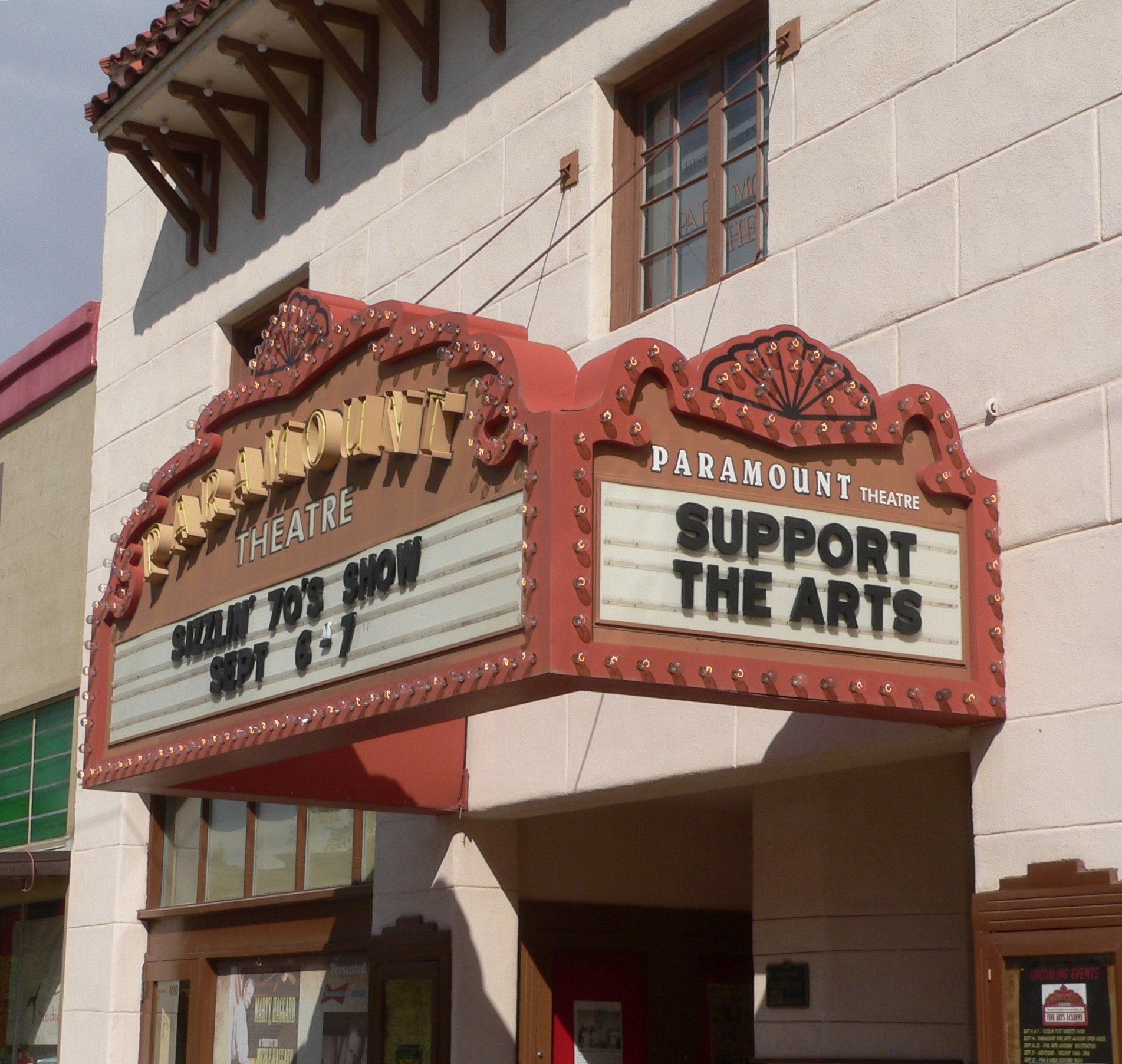 Außenansicht des Paramount Theatre in Sacramento, Kalifornien, mit Glasfenstern und -türen und einer "Support the Arts"-Schrifttafel über dem Eingang, vor einem sichtbaren Himmel.