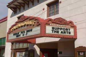 Außenansicht des Paramount Theatre in Sacramento, Kalifornien, mit Glasfenstern und -türen und einer "Support the Arts"-Schrifttafel über dem Eingang, vor einem sichtbaren Himmel.