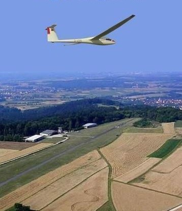 Ein Segelflugzeug, das über einem Feld mit Bäumen und Gebäuden im Hintergrund fliegt, mit Text oben auf dem Bild.