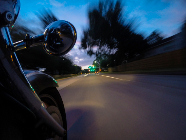 Ein Fahrrad ist auf der linken Seite des Bildes positioniert, mit einer Straße in der Mitte, Bäumen im Hintergrund und einer Wand auf der rechten Seite.